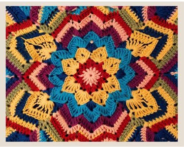 a flower granny square in red, blues, yellow, and peach colors.