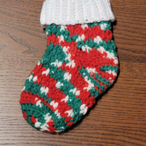 Medium sized holiday stocking in festive red, green, and white yarn with a white cuff