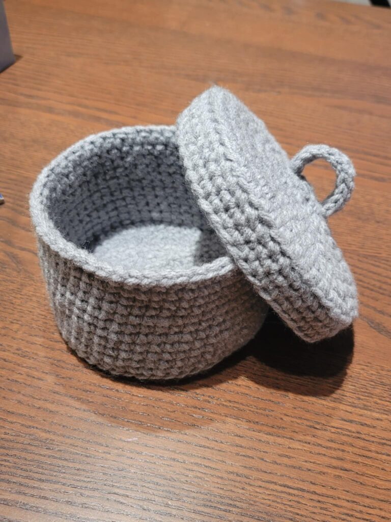 Crocheted tabletop scrap yarn bin with matching lid in gray color worsted weight yarn.
