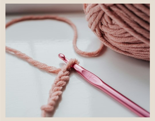 pink crochet hook made of aluminum with pink yarn